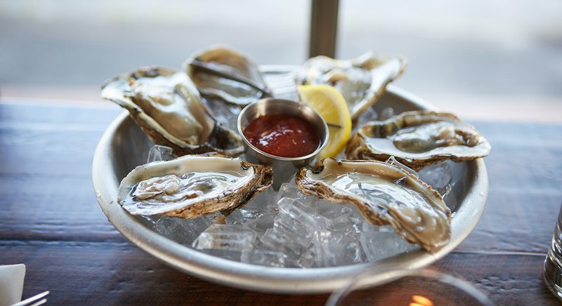  A plate of shucked oysters sits on a restaurant table. 